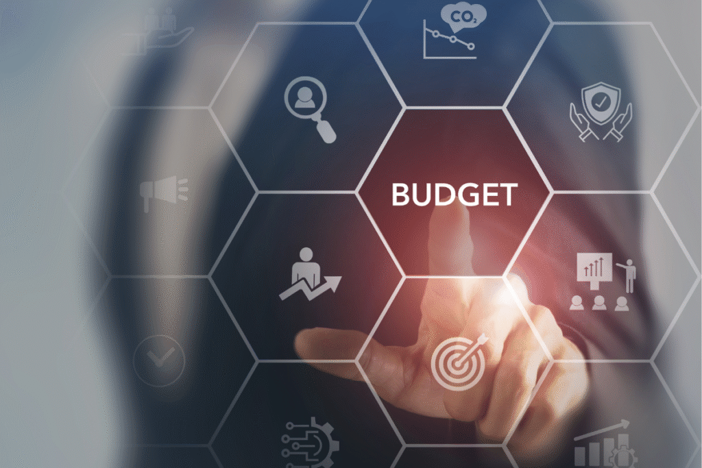Palec wskazujący na słowo „Budget” w cyfrowym interfejsie – symbol planowania budżetu reklamowego.