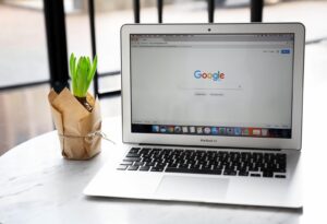 Ekran laptopa z otwartą stroną Google na tle biurka – symbol wyszukiwania i analizy danych reklamowych online.
