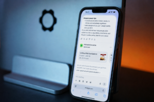 Telefon z ekranem prezentującym reklamę sponsorowaną w ChatGPT, stojący na biurku w nowoczesnym wnętrzu.